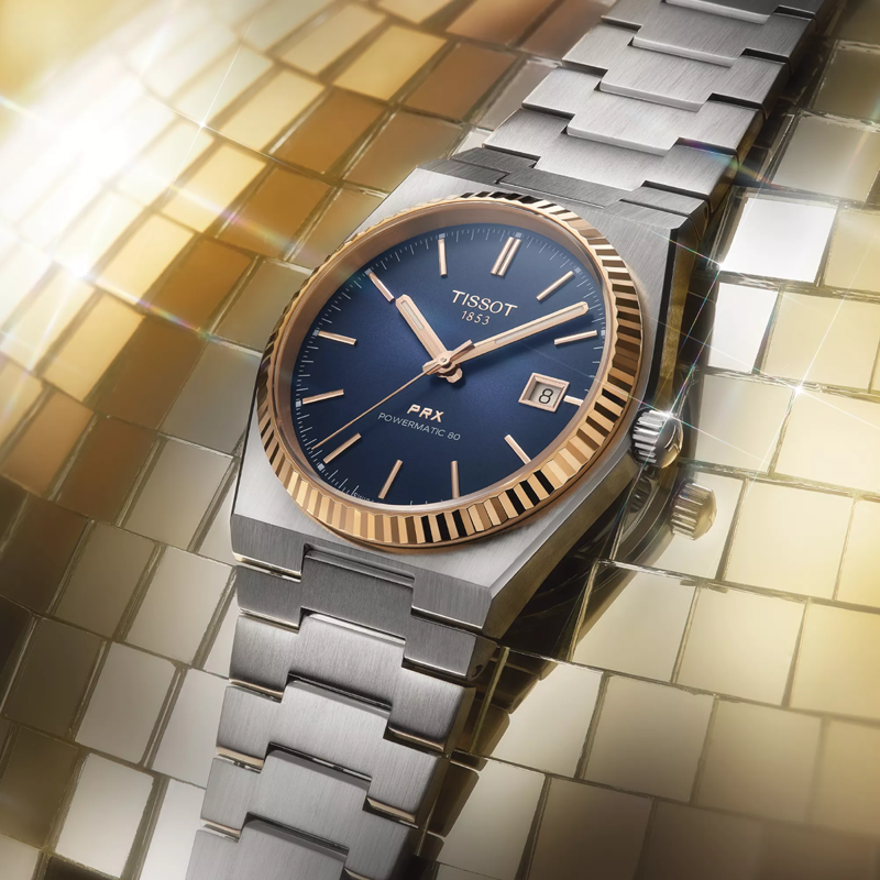 Tissot PRX Powermatic 80 Steel & 18K Gold Bezel 40mm watch on a coloured background